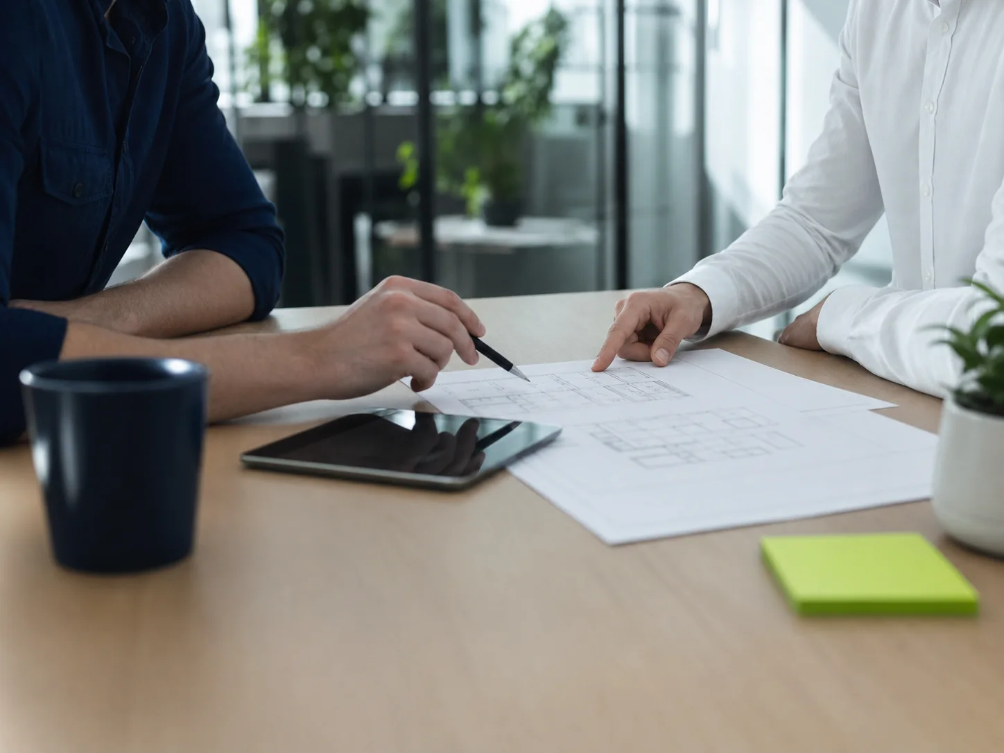 Profissionais analisando juntos uma planta durante uma conversa comercial.